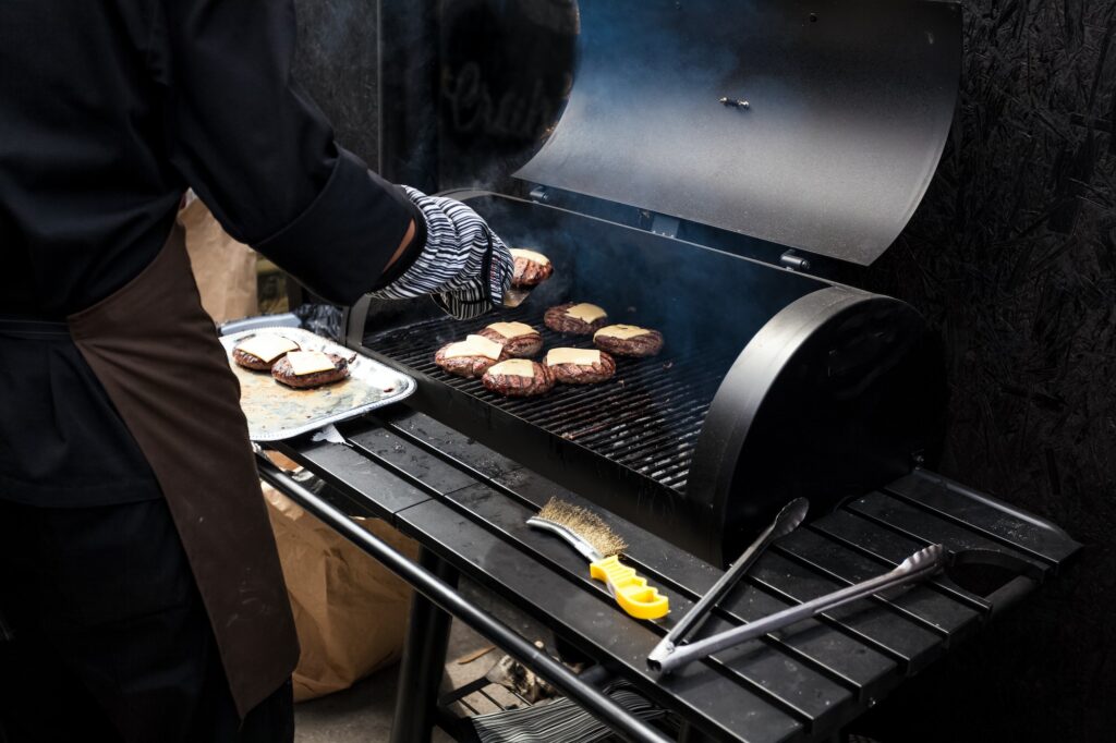 photo of man cooking burgers on big grill