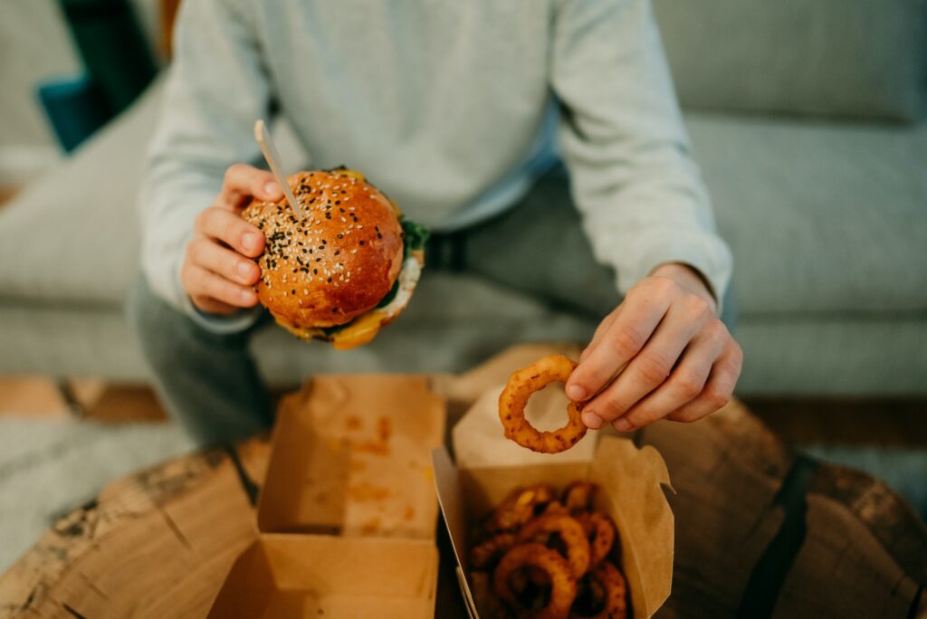 Man eating a burger and onion rings