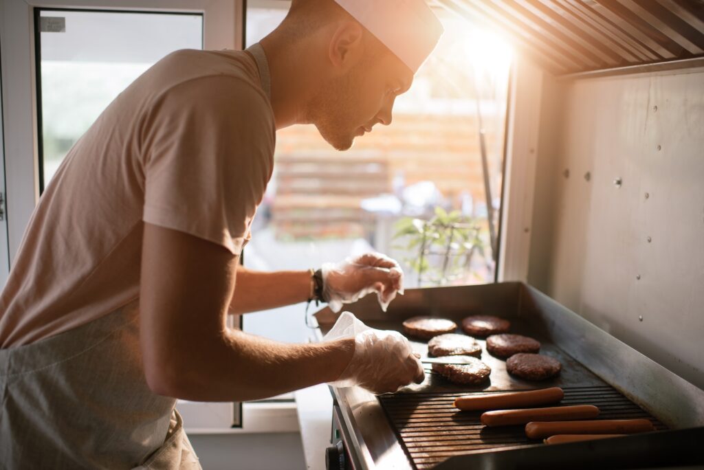 side view of chef preparing meat for burgers in food truck