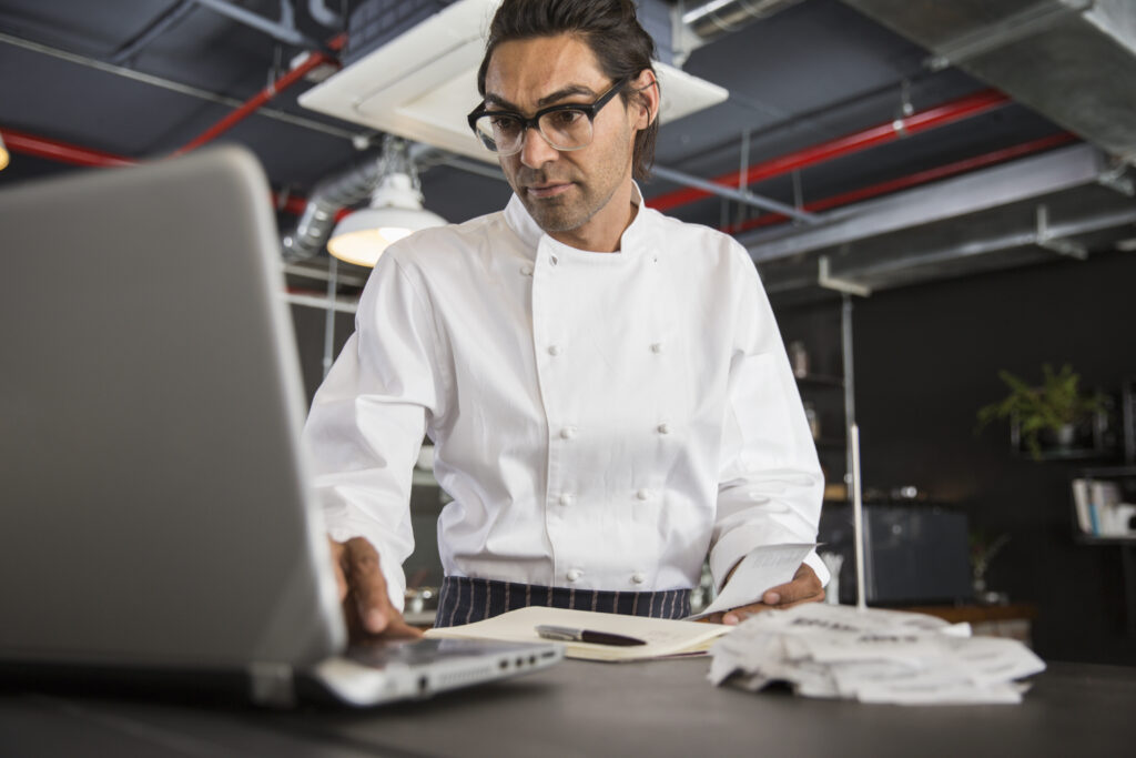 Chef in restaurant using laptop