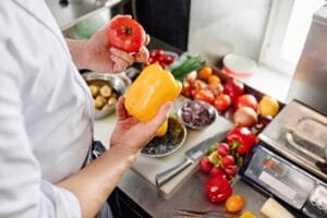 Cozinheiro selecionando vegetais frescos sobre a bancada de trabalho