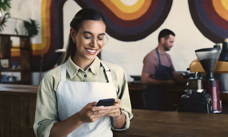 Gestora de restaurante usando celular para acompanhar relacionamento com clientes
