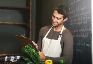 Profissional de cozinha consulta uma prancheta para conferir ingredientes no restaurante