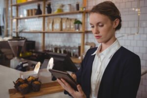 Recepcionista de restaurante consultando reservas em um tablet no balcão
